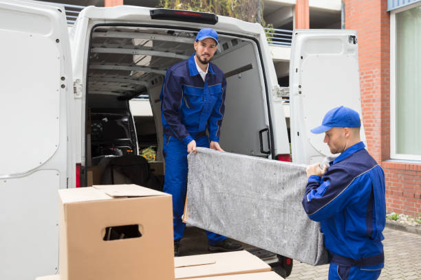 Two Young Male Worker In Blue Uniform Unloading Furniture From Truck